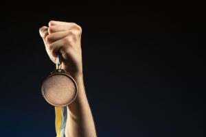 Atleta segurando medalha de ouro sobre fundo escuro